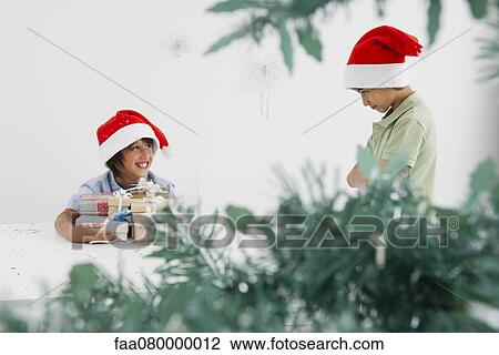 Boy holding armful of Christmas presents, smiling mischievously at sulky brother View Large Photo Image Stock Image - Boy holding armful of Christmas presents, smiling mischievously at sulky brother. Fotosearch