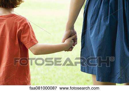 Stock Photo - Boy holding mother's hand, rear view. Fotosearch