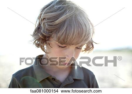 Picture - Boy outdoors, looking down in thought. Fotosearch