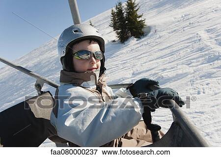 Boy riding ski lift at ski resort View Large Photo Image Stock Photo - Boy riding ski lift at ski resort. Fotosearch