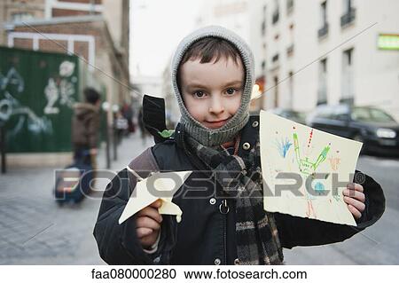 Stock Image - Boy showing his drawing and origami crane. Fotosearch