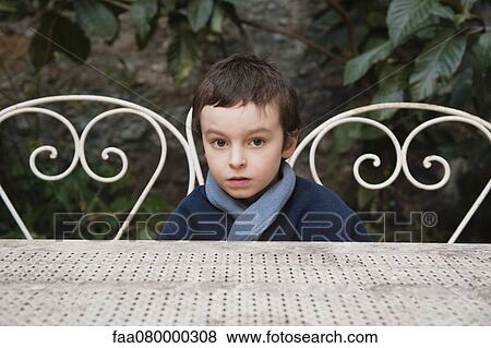 Stock Photo - Boy sitting at table outdoors, portrait. Fotosearch