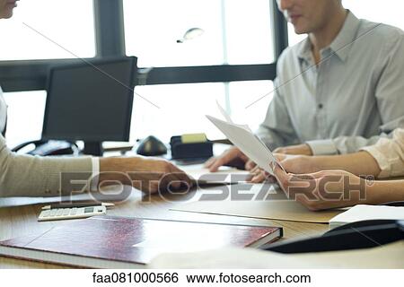 Stock Photograph - Business associates negotiating in meeting, cropped. Fotosearch
