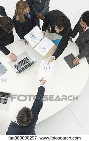 Stock Photo - Business associates reviewing documents in meeting. Fotosearch