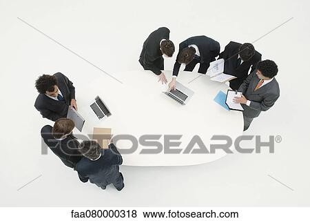 Stock Photo - Business associates working together in groups around table. Fotosearch