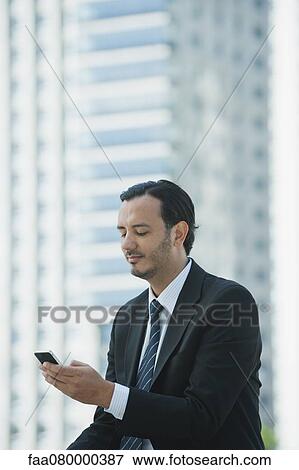 Business executive text messaging with cell phone outdoors View Large Photo Image Stock Photo - Business executive text messaging with cell phone outdoors. Fotosearch