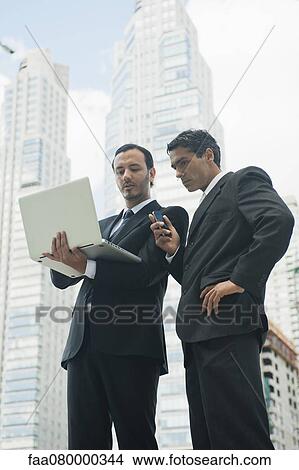 Picture - Business executives using laptop computer outdoors. Fotosearch