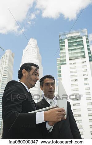 Stock Photo - Business executives using laptop computer outdoors. Fotosearch