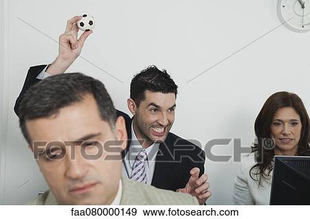 Business people in office, young businessman throwing mini soccer ball View Large Photo Image Stock Photo - Business people in office, young businessman throwing mini soccer ball. Fotosearch