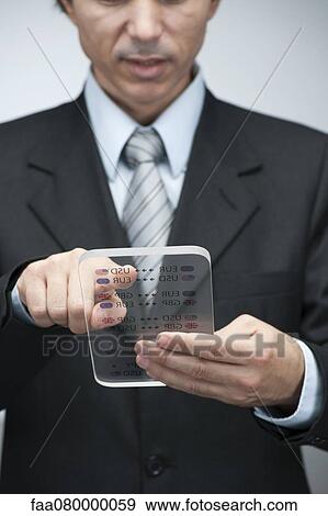 Stock Photo - Businessman reading business data on advanced digital tablet, cropped. Fotosearch