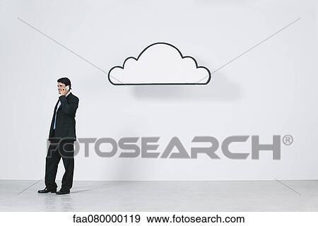 Stock Photo - Businessman talking on cell phone near graphic cloud representing cloud computing. Fotosearch