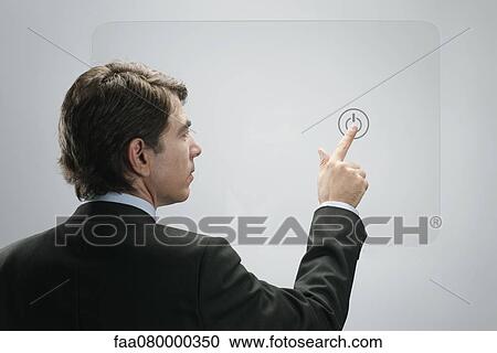Stock Image - Businessman touching power button on advanced touch screen interface. Fotosearch