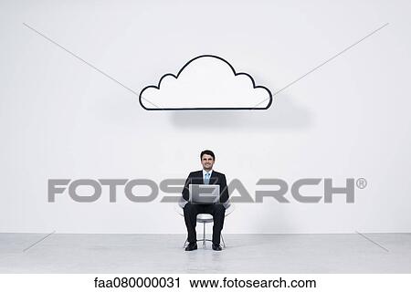 Stock Image - Businessman using laptop computer beneath cloud representing cloud computing. Fotosearch