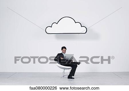 Businessman using laptop computer beneath cloud representing cloud computing View Large Photo Image Stock Photograph - Businessman using laptop computer beneath cloud representing cloud computing. Fotosearch