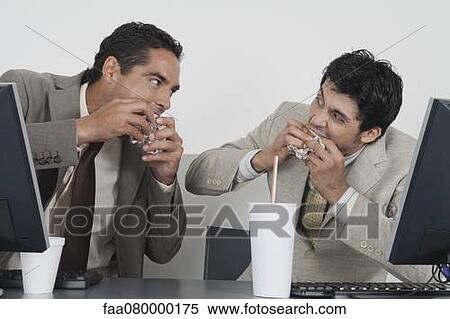 Businessmen eating fast food at desk in office View Large Photo Image Stock Photography - Businessmen eating fast food at desk in office. Fotosearch