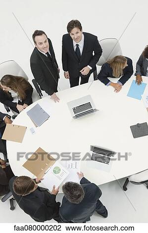 Businessmen working with associates at meeting View Large Photo Image Stock Image - Businessmen working with associates at meeting. Fotosearch