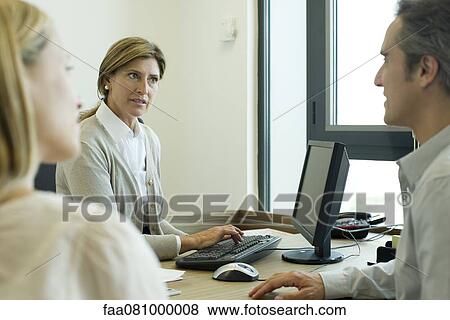 Stock Photo - Businesswoman assisting clients in office. Fotosearch