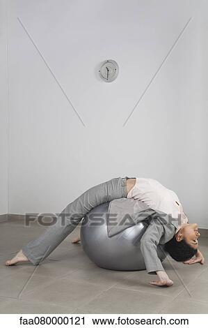 Businesswoman exercising on fitness ball in office View Large Photo Image Stock Image - Businesswoman exercising on fitness ball in office. Fotosearch