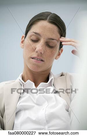 Stock Photo - Businesswoman holding head, eyes closed. Fotosearch