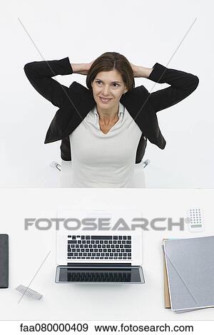 Stock Photo - Businesswoman relaxing at desk, high angle view. Fotosearch