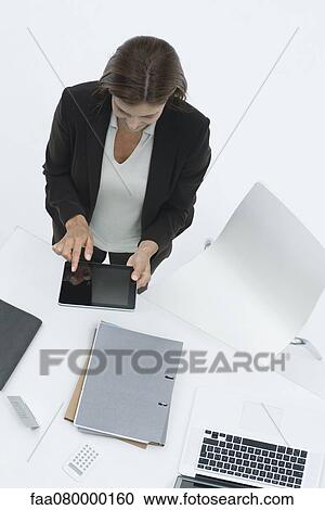 Businesswoman standing by desk using digital tablet View Large Photo Image Stock Image - Businesswoman standing by desk using digital tablet. Fotosearch