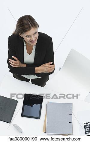 Businesswoman standing by desk with arms folding, high angle view View Large Photo Image Stock Image - Businesswoman standing by desk with arms folding, high angle view. Fotosearch