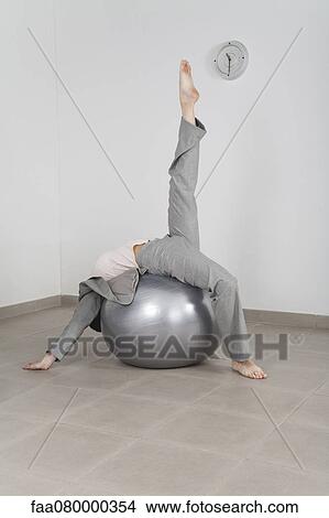 Businesswoman stretching on fitness ball in office View Large Photo Image Picture - Businesswoman stretching on fitness ball in office. Fotosearch