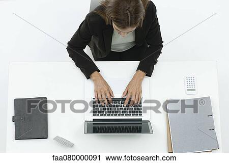 Stock Image - Businesswoman using laptop computer, overhead view. Fotosearch