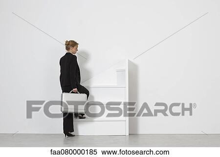 Stock Photography - Businesswoman walking up incomplete staircase, rear view. Fotosearch