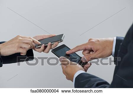 Colleagues exchanging information with smartphones, cropped View Large Photo Image Picture - Colleagues exchanging information with smartphones, cropped. Fotosearch