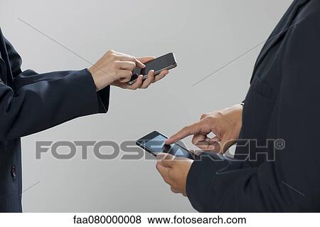 Colleagues exchanging information with smartphones, cropped View Large Photo Image Stock Photo - Colleagues exchanging information with smartphones, cropped. Fotosearch