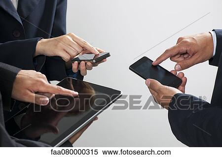Stock Photography - Colleagues exchanging information with smartphones and digital tablet, cropped. Fotosearch