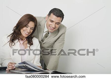 Colleagues looking at magazine together View Large Photo Image Picture - Colleagues looking at magazine together. Fotosearch