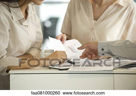 Colleagues reviewing documents together, cropped View Large Photo Image Stock Image - Colleagues reviewing documents together, cropped. Fotosearch