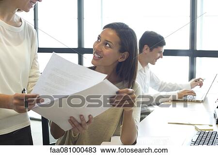 Stock Image - Colleagues reviewing documents together. Fotosearch