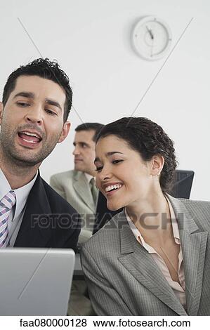 Stock Photo - Colleagues working on laptop computer. Fotosearch