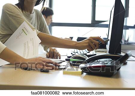 Stock Image - Colleagues working together on computer, cropped. Fotosearch