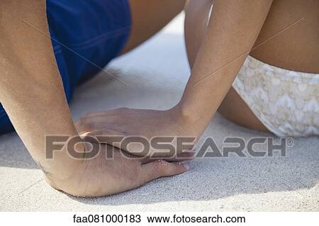 Stock Image - Couple holding hands at the beach, cropped. Fotosearch