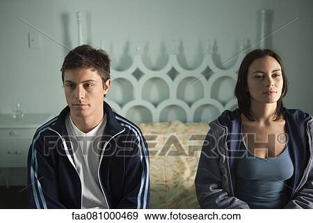 Stock Photo - Couple sitting on bed, both looking away in thought. Fotosearch