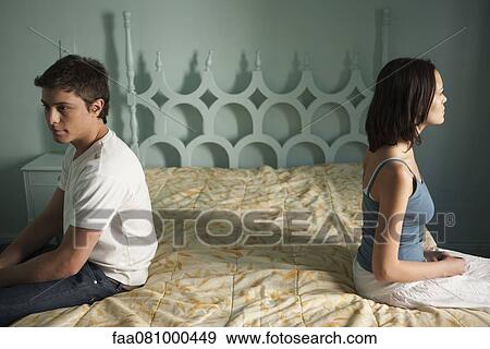 Couple sitting on separate sides of bed, both looking away View Large Photo Image Stock Photo - Couple sitting on separate sides of bed, both looking away. Fotosearch