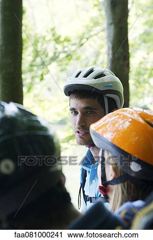 Stock Image - Cyclists hanging out together, focus on man. Fotosearch