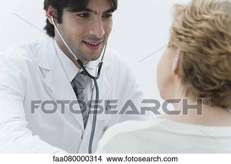 Picture - Doctor examining patient using stethoscope. Fotosearch