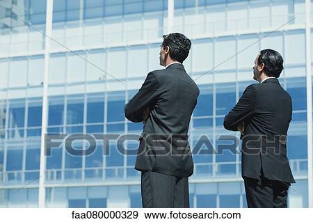 Stock Photo - Executives standing by office building with arms folded. Fotosearch