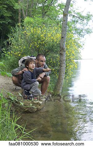 Stock Image - Father and son by river. Fotosearch