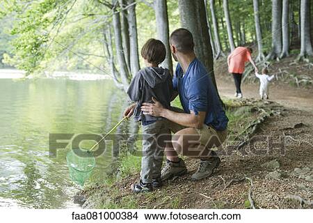 Picture - Father and son fishing in woods, both looking away. Fotosearch
