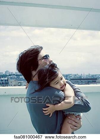 Stock Photo - Father embracing young daughter outdoors. Fotosearch