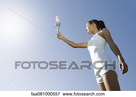 Female athlete holding up torch, low angle view View Large Photo Image Stock Photo - Female athlete holding up torch, low angle view. Fotosearch