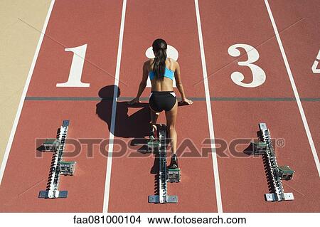 Female athlete in starting position on running track, rear view View Large Photo Image Picture - Female athlete in starting position on running track, rear view. Fotosearch