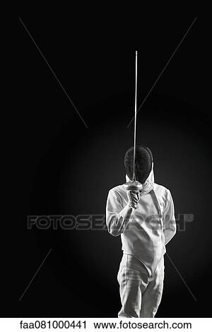 Stock Image - Fencer holding up foil, portrait. Fotosearch