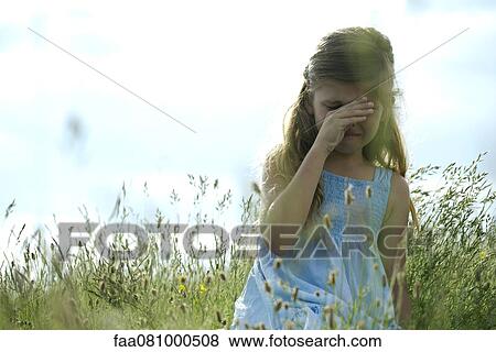 Girl crying in field, hand rubbing eyes View Large Photo Image Stock Photo - Girl crying in field, hand rubbing eyes. Fotosearch
